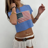 Person wearing a blue t-shirt with an American flag design and a white skirt.
